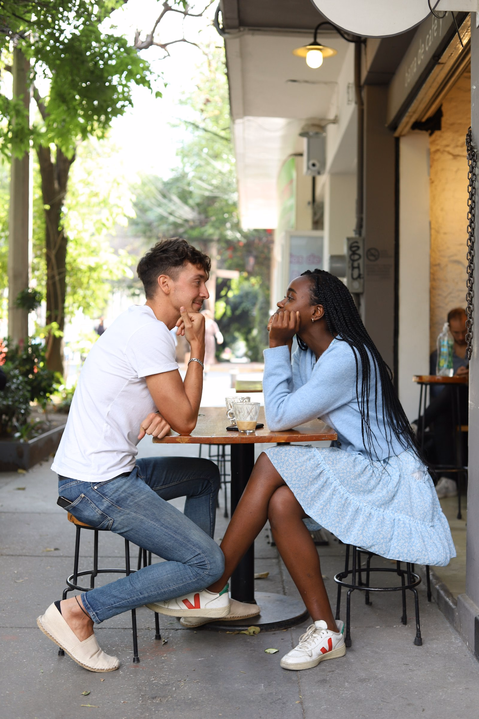 Couple talking and laughing across a table at a street café